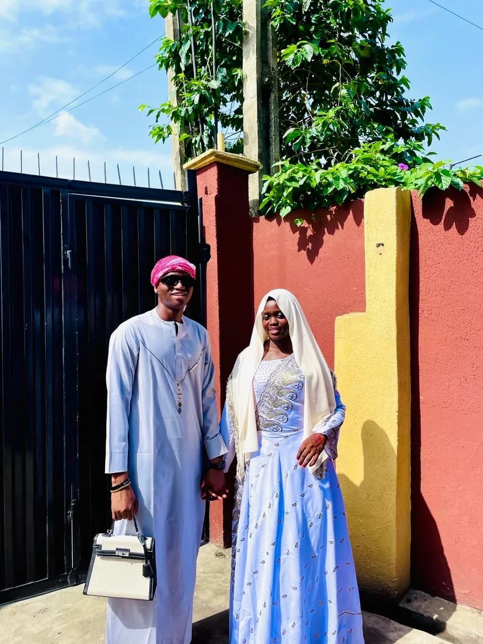 Abdulsalam and Sofiyyah, hand in hand, in pale blue and white